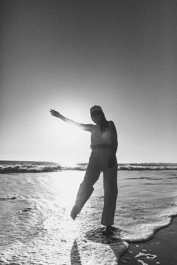 Black and white silhouette of a woman dancing in the surf at a Santa Barbara beach